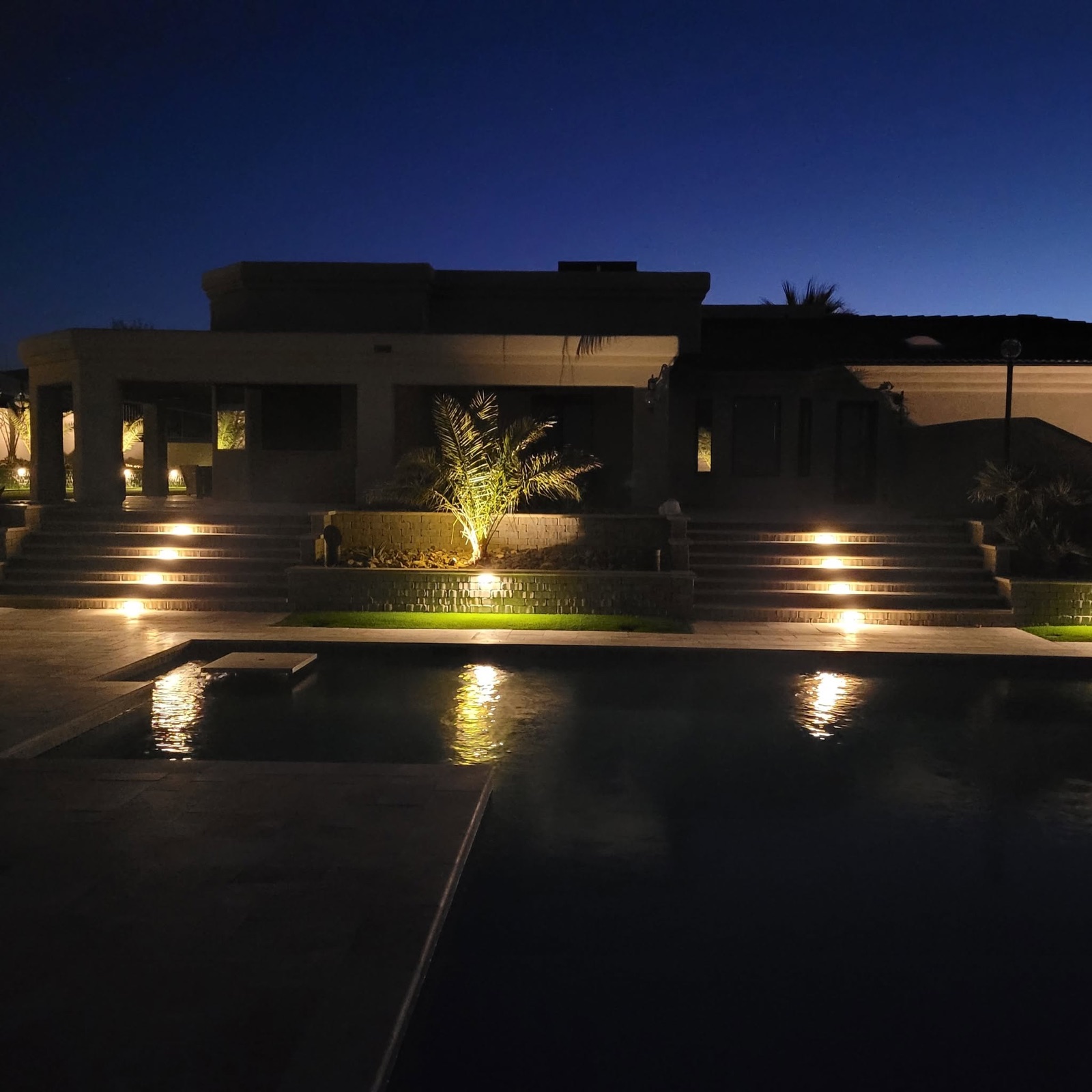 Finished pool deck and lit paver steps at night — a Havasu Pavers backyard in Lake Havasu City