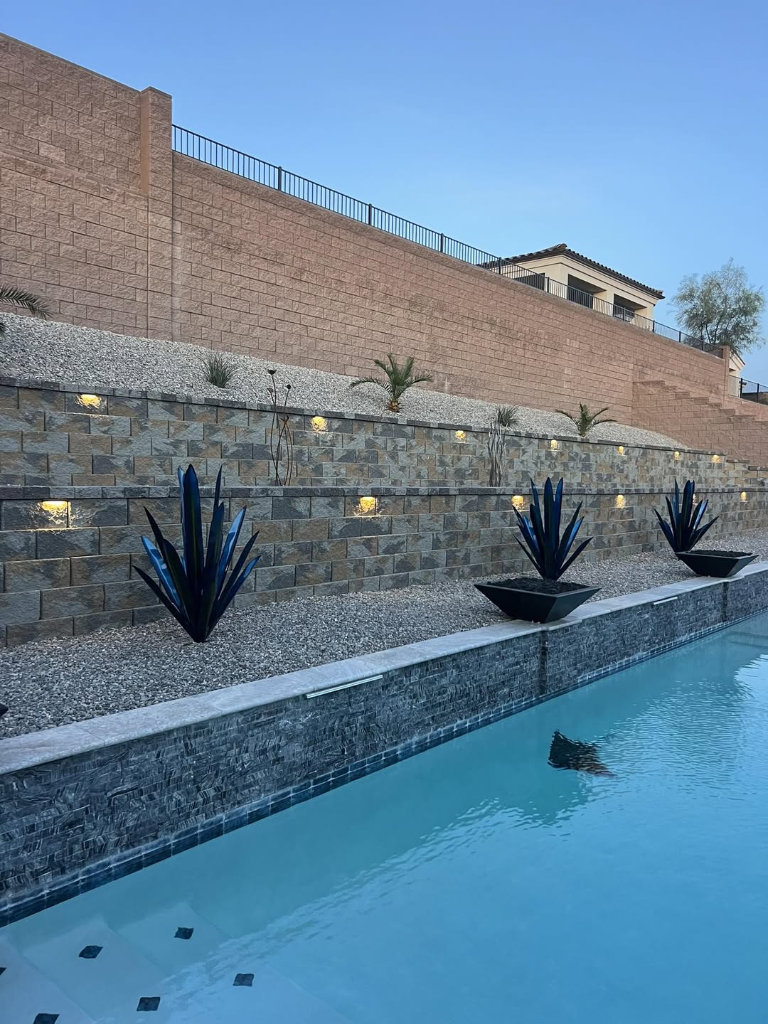 Tiered block retaining walls with landscape lighting beside a pool — Havasu Pavers in Lake Havasu City
